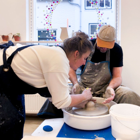 Een cursist zittend achter een draaischijf krijgt instructies van de docent tijdens de workshop basistechnieken