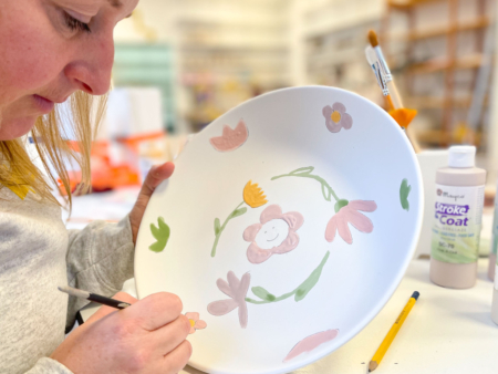 Workshop deelnemer beschildert een schaal met bloemen met een penseel en glazuur