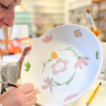 Workshop deelnemer beschildert een schaal met bloemen met een penseel en glazuur