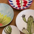 resultaten van workshop Amazing Glaze: 4 borden met beschilderingen van cactussen, een tros tomaten en een zonnebloem